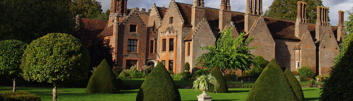 Chenies Manor in early autumn afternoon light - all green trees and topiary- topiary