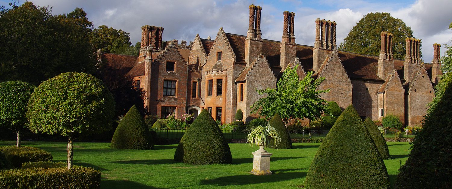 Chenies Manor in early autumn afternoon light - all green trees and topiary- topiary