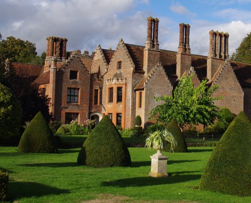 Chenies Manor in early autumn afternoon light - all green trees and topiary- topiary
