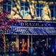 Brazils exterior - blue and gold signage, striped awning and cherry blossom tree in the foreground