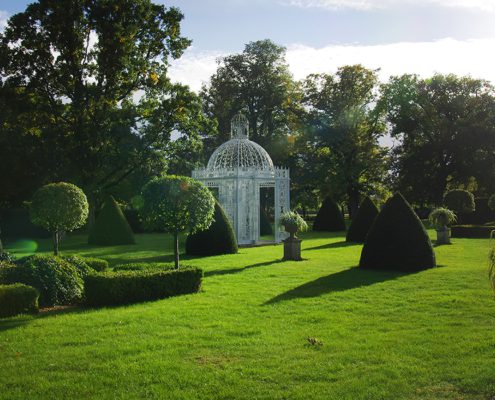 Gardens at Chenies manor- lawns, and topiary, and white painted ornate arbour
