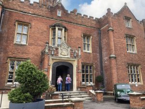View of the front door and front of building with two guests walking up the steps; vintage car in foreground