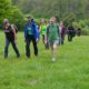 People walking up a gentle slope, border collie in the foreground