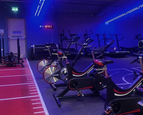 Dark blue lit gym with Wattbikes