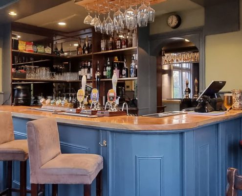 Interior of Cock and rabbit pub showing blur grey bar panelling, seating and pumps and glasses