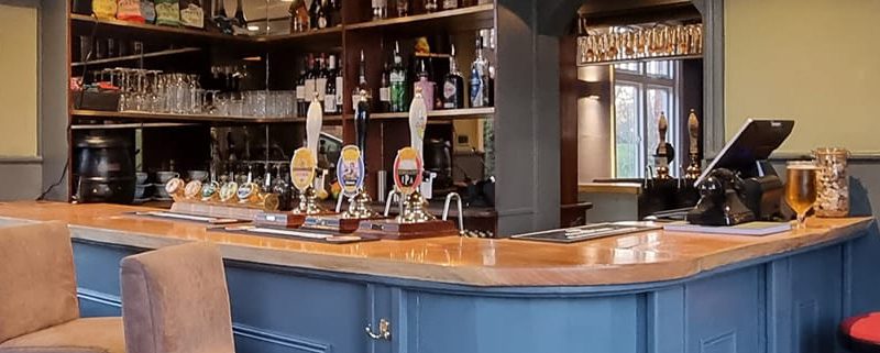 Interior of Cock and rabbit pub showing blur grey bar panelling, seating and pumps and glasses