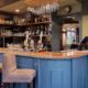 Interior of Cock and rabbit pub showing blur grey bar panelling, seating and pumps and glasses
