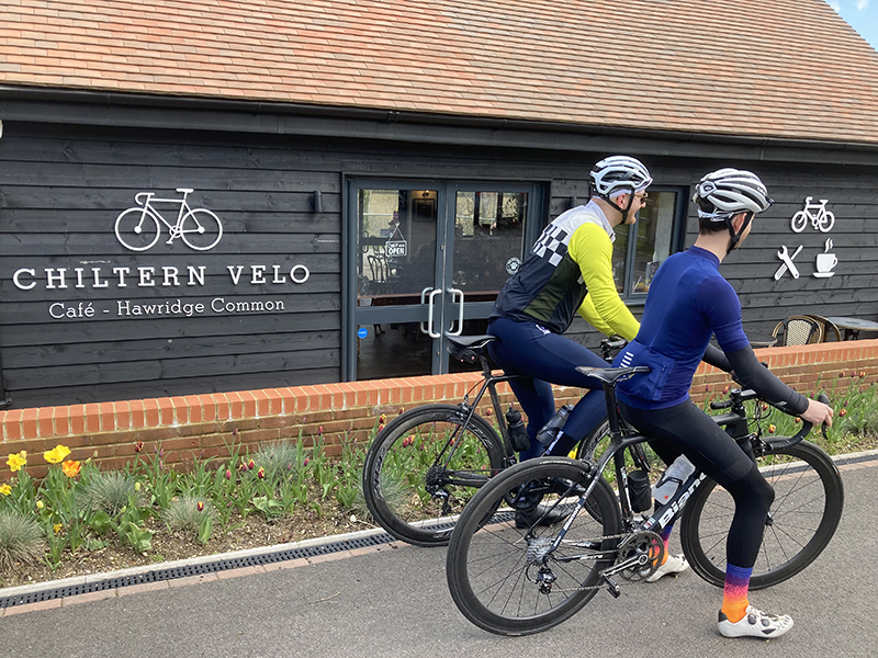 Two cyclists setting off, in front of Chiltern Velo cafe
