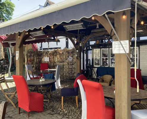 Outdoor seating under cover outside The Drawingroom. high backed red chairs, warm lighting