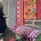 Owner standing with forecourt display of colourful rugs and cushions
