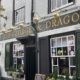 Outside ofThe george and Dragon pub with signage explaining its hostory dating back to the 16th century. The brick parapet facade and ornate bracketry were added in 1715.