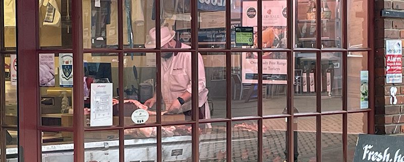 View through window of Gerry Martins window with butcher preparing meat slightly in view on the counter.
