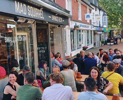 Mad squirrel frontage with many people sitting outside at rthe tavbles looking happy