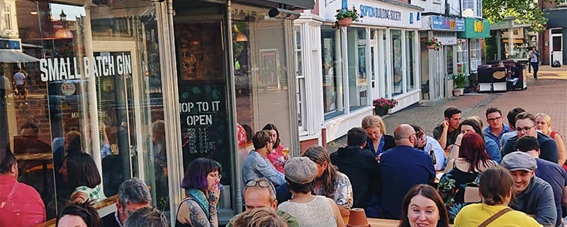 Mad squirrel frontage with many people sitting outside at rthe tavbles looking happy