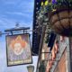 Pub sign depicting Queen Elizabeth the first, flowering hanging basket in the foreground