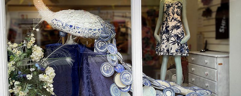 Window display in the ever-changing, ever-creative Rennie Hospice Shop. Here featuring a peacock sculpture with a tail made up of blue and white willow pattern plates