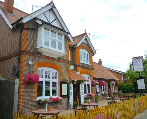 Exterior of The Griffin pub in summer with benches and hanging baskets