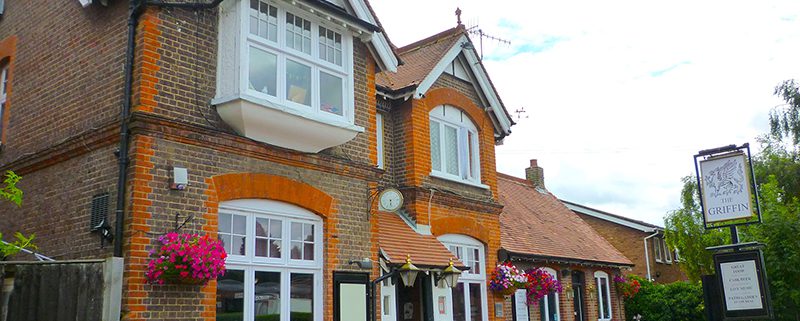 Exterior of The Griffin pub in summer with benches and hanging baskets