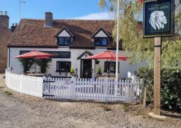 Exterior of the White Lion pub with parasols, pub sign and Spanish flag