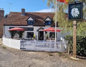 Exterior of the White Lion pub with parasols, pub sign and Spanish flag