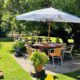 White Hart garden on a sunny day pub benches, round table with parasol, lawn and trees