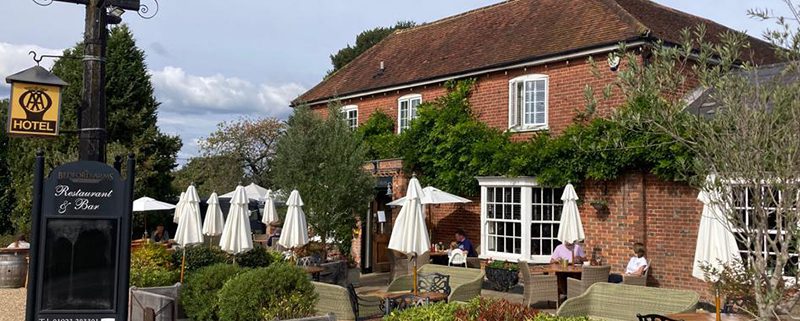Outside view of the Bedford Arms pub, Chenies, with pub sign and garden area.