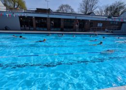 Outdoor pool with lanes and a few swimmers on a sunny day-bright clear water
