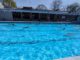 Outdoor pool with lanes and a few swimmers on a sunny day-bright clear water