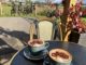 Two cappuccinos with a cocoa powder decoration of cycles with view of bikes and countryside behind