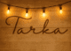 Tarka in cursive text on wooden panel with four fairy lights above