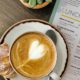 Cappuccino with heart in the froth, and pastry, with a menu underneath on wooden table