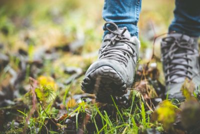 Close of of person's feet in walking boots in field