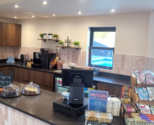 View of cafe with snacks in foreground and view through window of outdoor pool