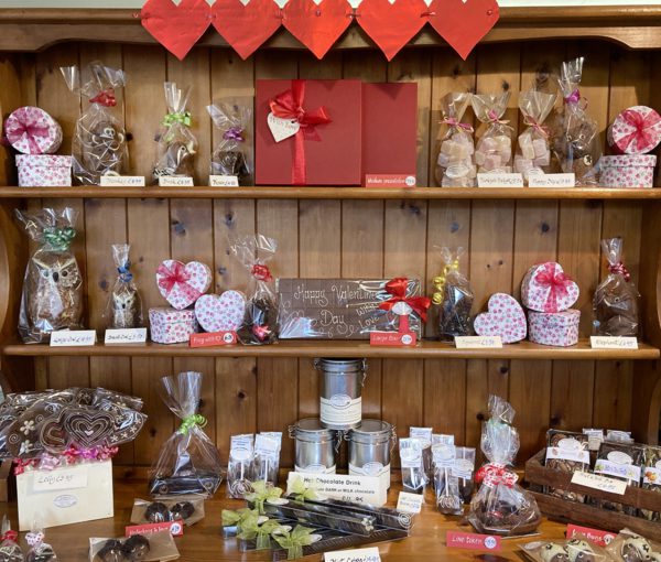 a Valentines display of chocolates on wooden dresser –chocolate bars and chocolate animals, and heart-shaped chocolate boxes