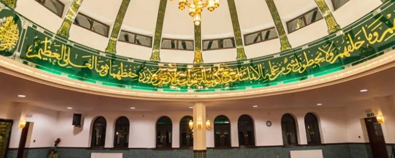 Interior or mosque showing dome, chandelier and partial inscription