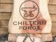 chiltern forgt logo carved into wood, with metalwork hook in the foreground