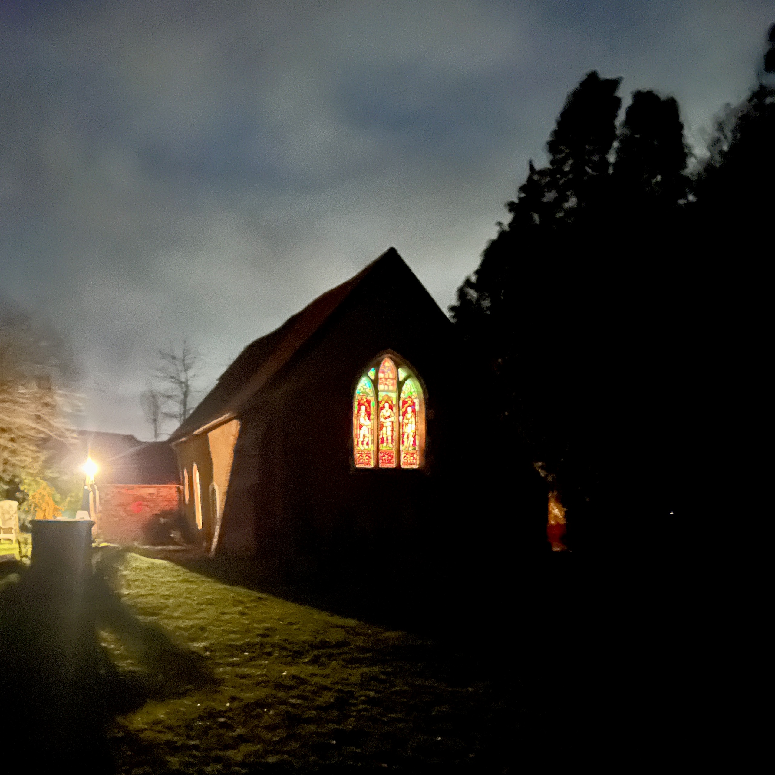 old church it lit up at night, light showing through stained glass windows